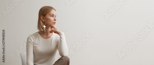 Fashionable girl in a white sweater and checkered pants . Natural lifestyle portrait of girl , emotional and fashion mood ,chic clothes and summer theme . Soft warm vintage color tone . Gold earrings