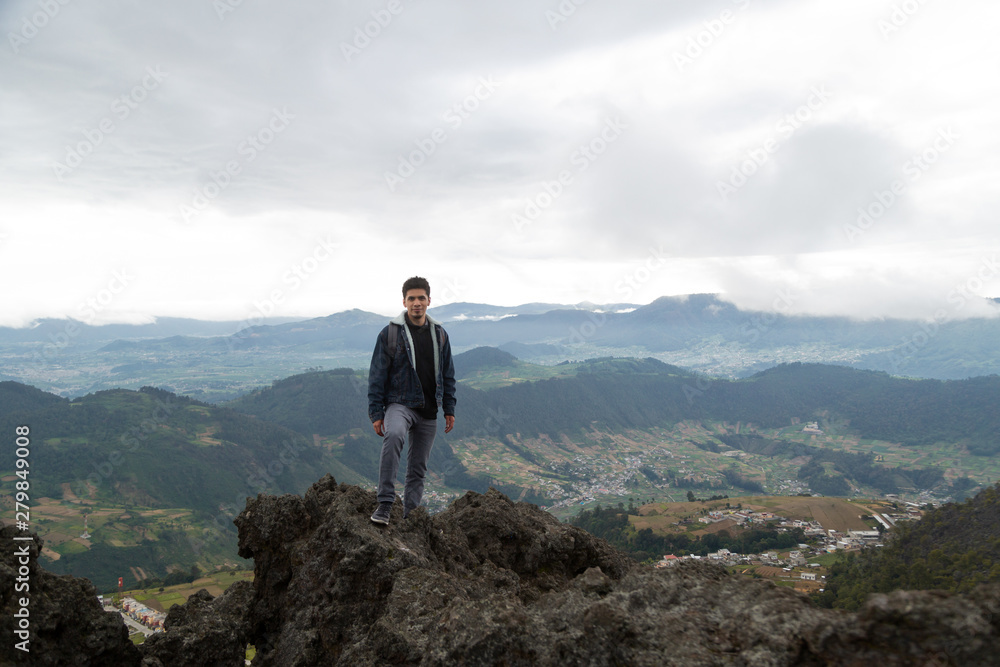 Hispanic man standing on top of a hill with mountains behind him - Hispanic man climbing