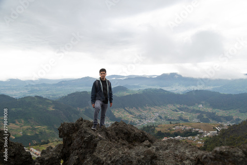 Hispanic man standing on top of a hill with mountains behind him - Hispanic man climbing