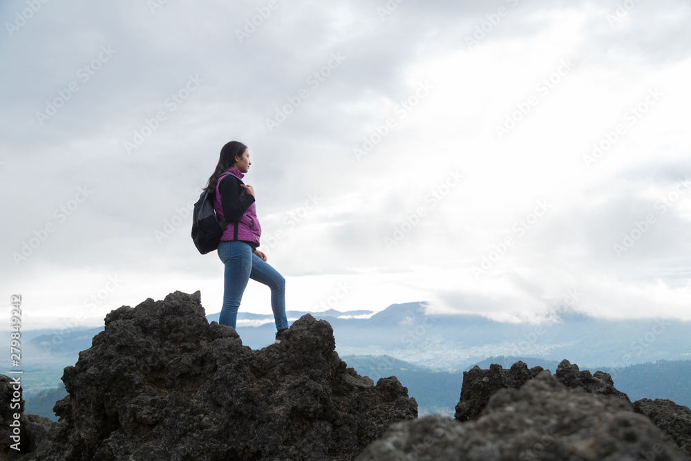 traveling woman standing on the top of a cliff overlooking the landscape- Hispanic woman