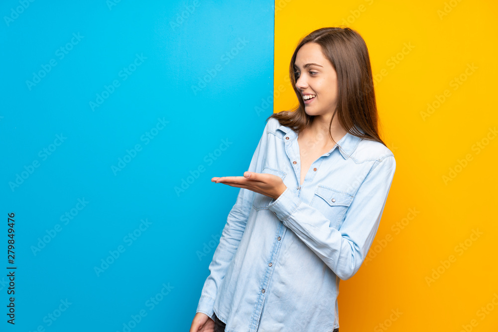 Young woman over colorful background extending hands to the side for inviting to come Young woman over colorful background extending hands to the side for inviting to come