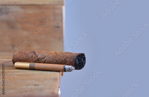 Burning handmade luxury Cuban cigar on an old wooden background with copyspace