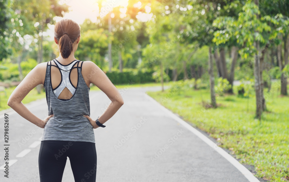 © sutthinon602 - Back view of young fitness woman running on the road in the morning, Young fitness sportswoman runner running on tropical park trail. People and sport concept. Fitness and healthy lifestyle concept. © sutthinon602 - Back view of young fitness woman running on the road in the morning, Young fitness sportswoman runner running on tropical park trail. People and sport concept. Fitness and healthy lifestyle concept.