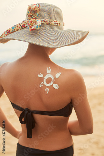 Suntan Lotion. Sexy Young Woman in Bikini  Applying Sunscreen Solar Cream.Sun Protection. Sun Cream. Skin and Body Care. Sunblock. Sun shape on the shoulder.
