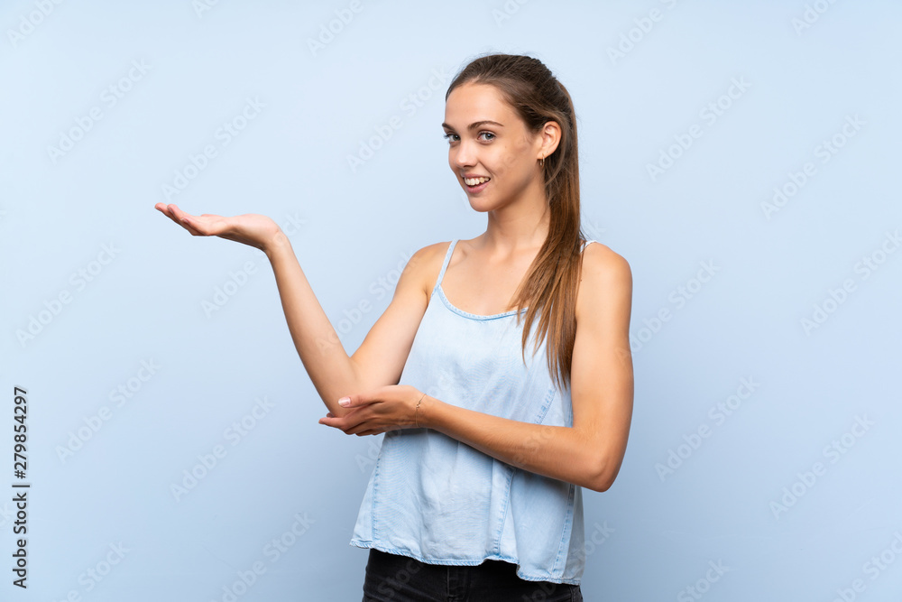 Young woman over isolated blue background extending hands to the side for inviting to come Young woman over isolated blue background extending hands to the side for inviting to come