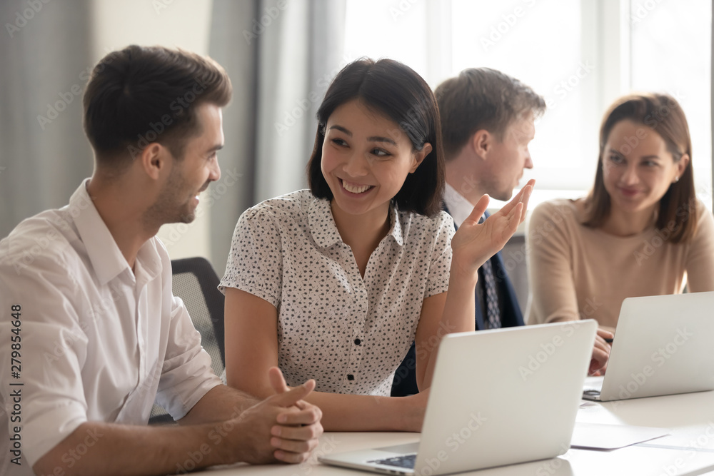 Happy diverse employees talking laughing working together with coworkers laptops Happy diverse employees talking laughing working together with coworkers laptops