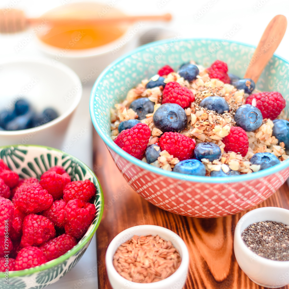 High protein healthy breakfast, buckwheat porridge with blueberries, raspberries, flax seeds and honey Closeup view, selective focus High protein healthy breakfast, buckwheat porridge with blueberries, raspberries, flax seeds and honey Closeup view, selective focus
