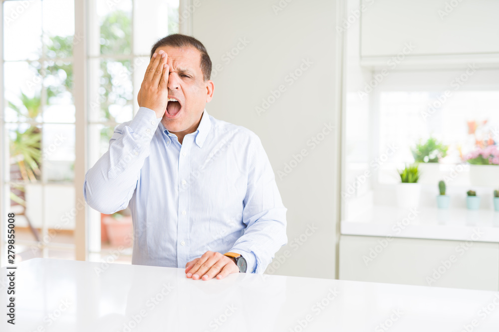 Middle age man sitting at home covering one eye with hand with confident smile on face and surprise emotion.