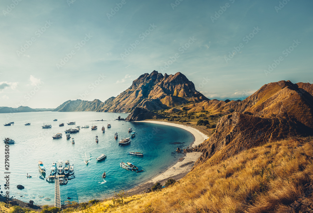 Obraz premium Mountains, ocean bay with boats. Aerial shot. Padar. Wonderful panoramic overview bay with the sand beaches surrounded by the mountains. Landscape of Padar island. Komodo National Park. Indonesia.
