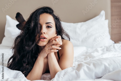 фотографія front view of sexy undressed young woman lying in bed in bedroom