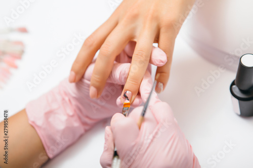 Manicure creation process. Closeup shot of a woman in a nail salon receiving a manicure by a beautician with nail file. Woman getting nail manicure. Beautician file nails to a customer.