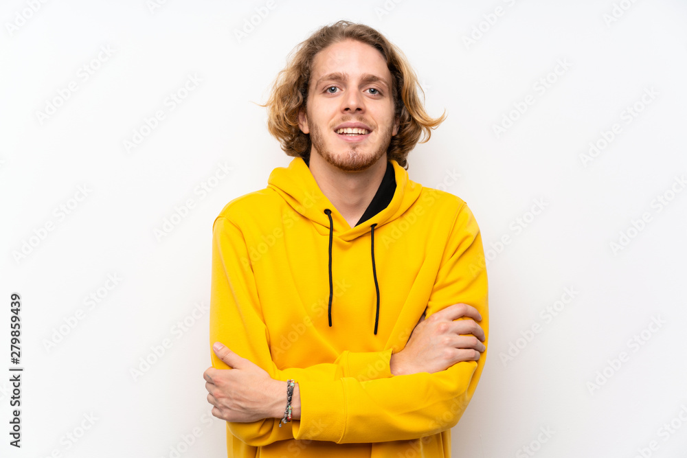 Blonde man with sweatshirt over white wall keeping the arms crossed in frontal position Blonde man with sweatshirt over white wall keeping the arms crossed in frontal position