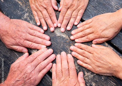 a group of hands touch to formalize their friendship. Caucasian people women and men. Dark wooden table on background photo