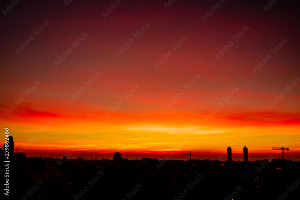 Beautiful orange sunset sky. Panorama view of Barcelona city in Spain with dramatic light.