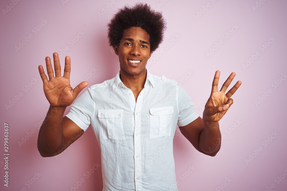 Young american man with afro hair wearing white shirt standing over isolated pink background showing and pointing up with fingers number eight while smiling confident and happy. Young american man with afro hair wearing white shirt standing over isolated pink background showing and pointing up with fingers number eight while smiling confident and happy.