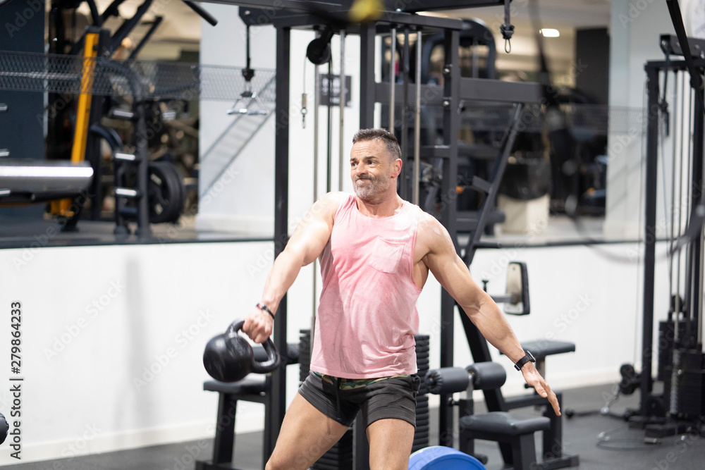 Very strong man lifting ball weights in gym. Very strong man lifting ball weights in gym.
