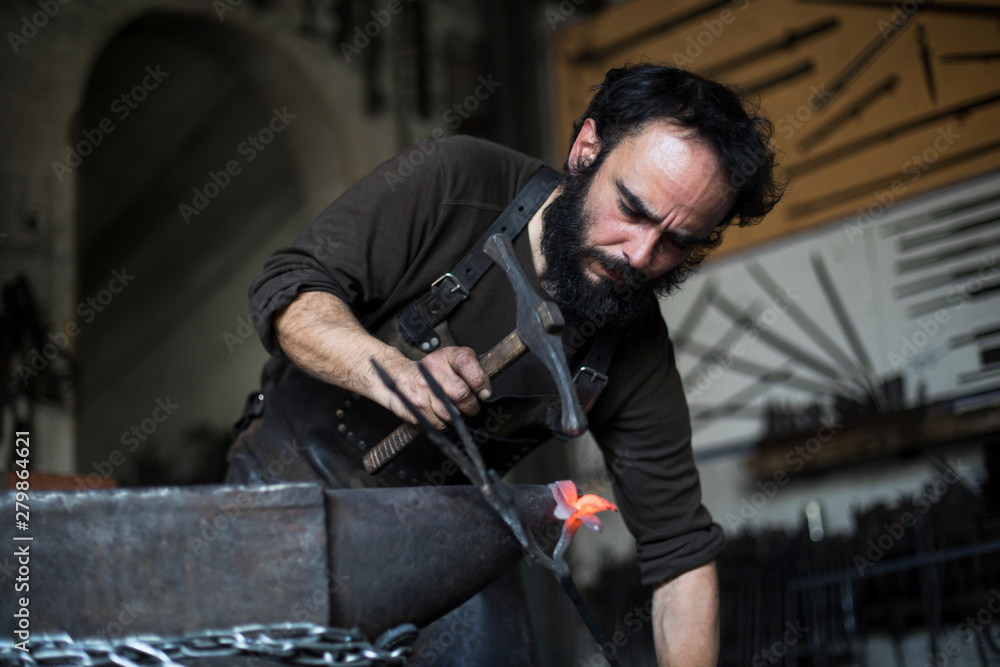 Blacksmith forging metal in workshop Blacksmith forging metal in workshop