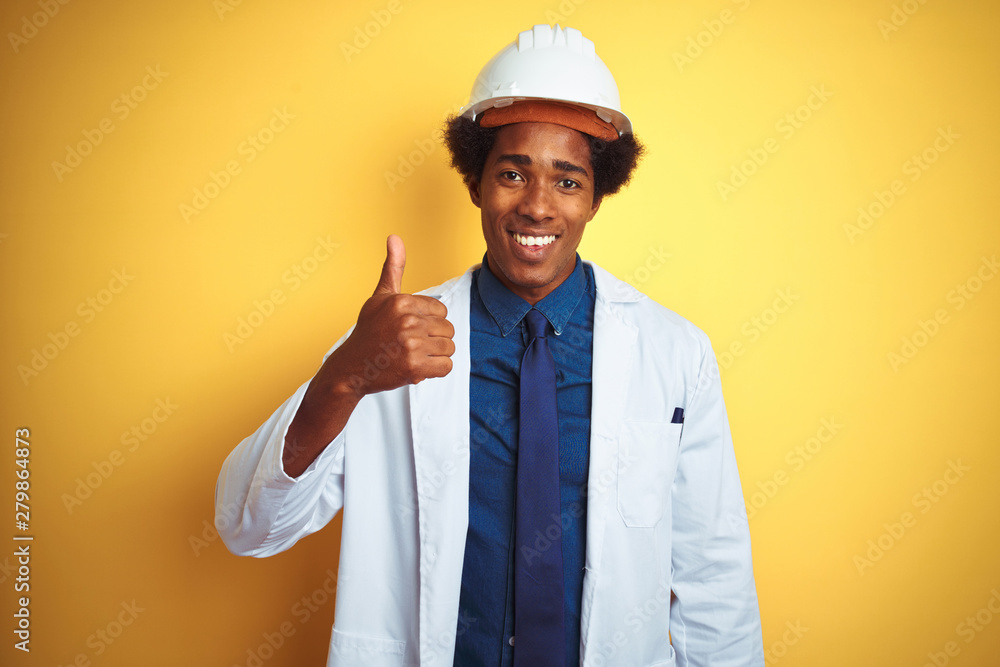 Afro american engineer man wearing white coat and helmet over isolated yellow background doing happy thumbs up gesture with hand. Approving expression looking at the camera with showing success. Afro american engineer man wearing white coat and helmet over isolated yellow background doing happy thumbs up gesture with hand. Approving expression looking at the camera with showing success.
