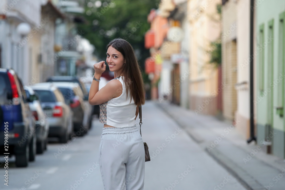 Young fashionable woman posing on the street in the summer evening	