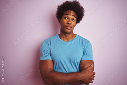 African american man with afro hair wearing blue t-shirt standing over isolated pink background smiling looking to the side and staring away thinking.