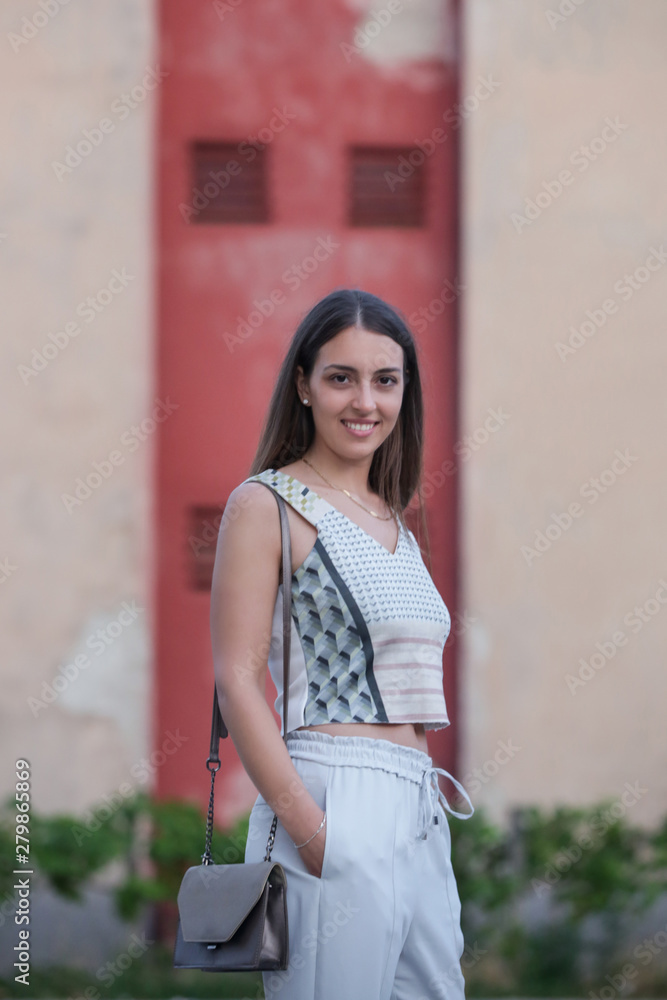 Young fashionable woman posing on the street in the front of the building facade