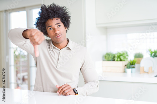 African American man at home looking unhappy and angry showing rejection and negative with thumbs down gesture. Bad expression.