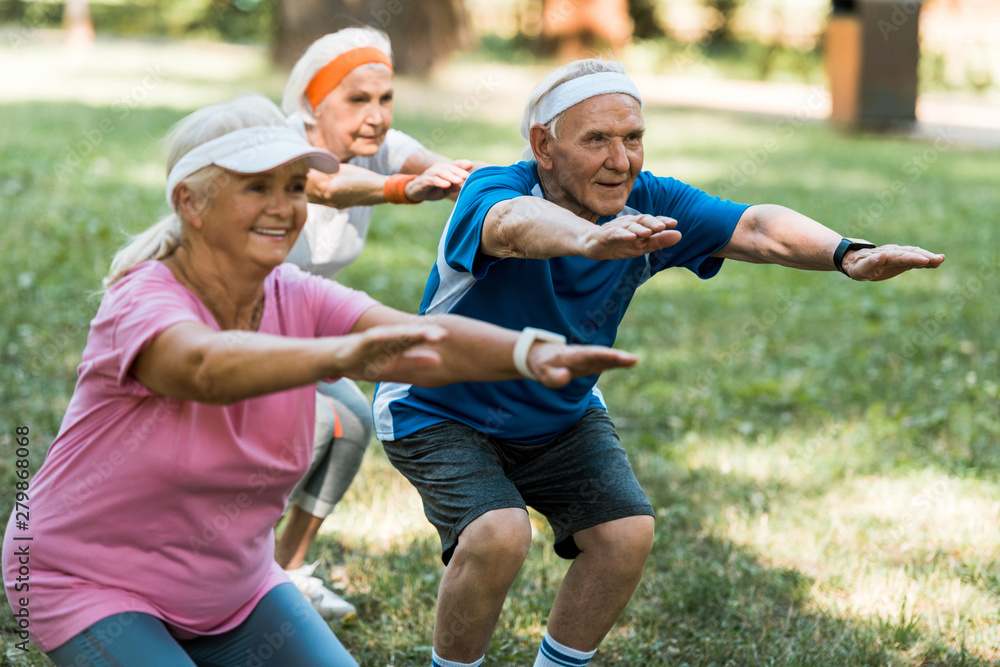 selective focus of retired man doing sit ups with senior women