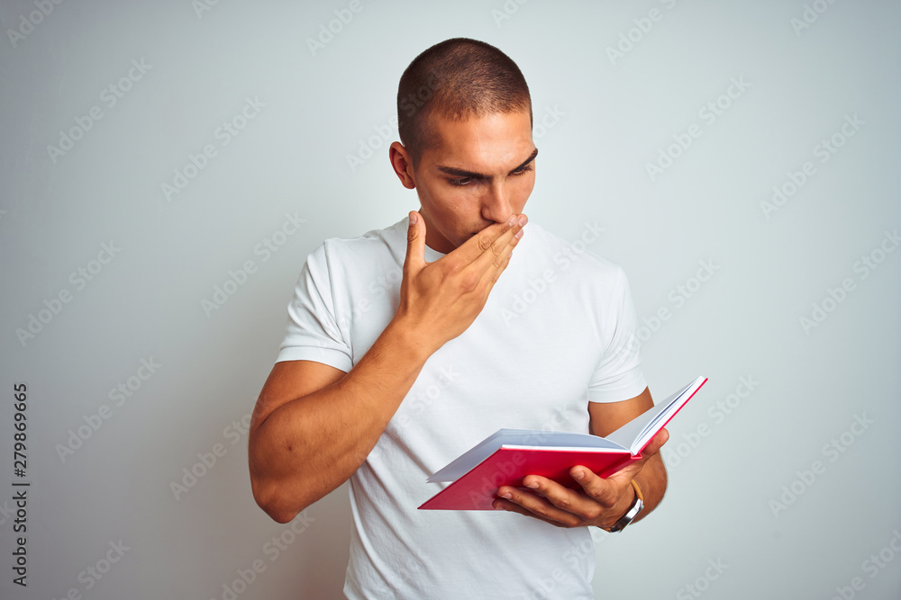 Young handsome man reading red book over white isolated background cover mouth with hand shocked with shame for mistake, expression of fear, scared in silence, secret concept Young handsome man reading red book over white isolated background cover mouth with hand shocked with shame for mistake, expression of fear, scared in silence, secret concept