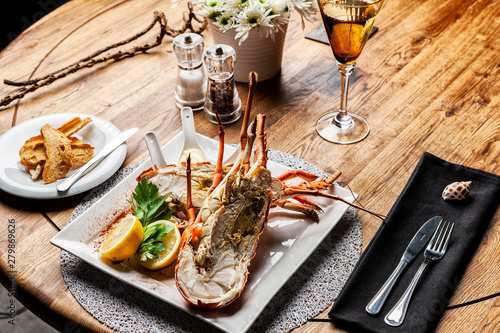 Fabulous lobster dish on wooden table with wine and all the finesse of a luxury restaurant. photo