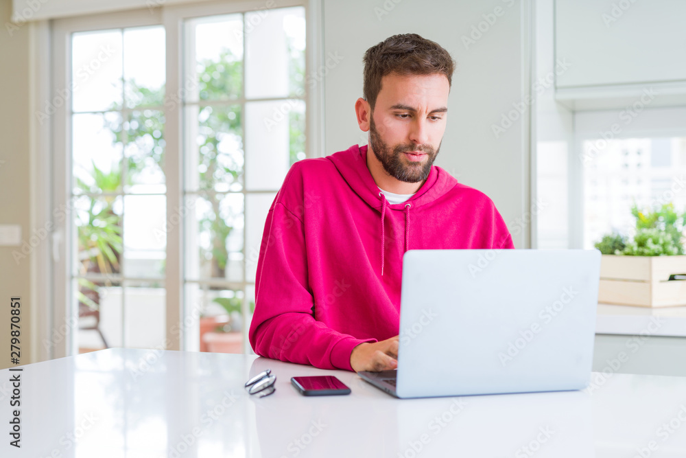 Handsome man working using computer laptop with serious expression on face. Simple and natural looking at the camera. Handsome man working using computer laptop with serious expression on face. Simple and natural looking at the camera.
