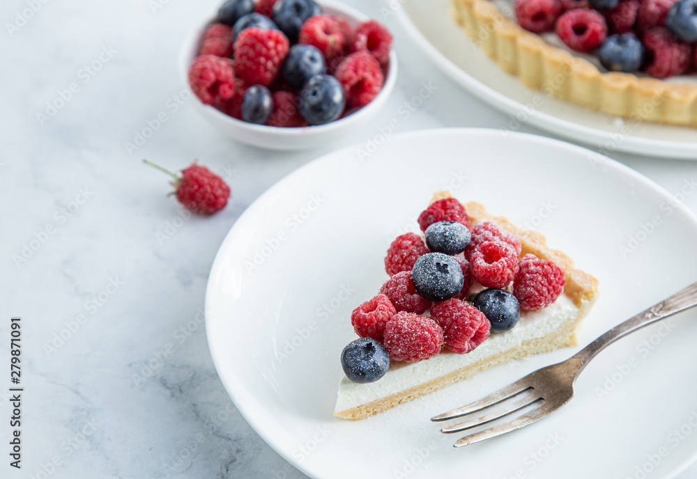 slice of blueberry and raspberry tart on white marble background slice of blueberry and raspberry tart on white marble background