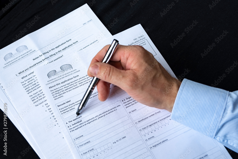 Writes legal documents to the European Court. Filing a complaint to a higher European court. A man writes a legal document with a pen. Writes legal documents to the European Court. Filing a complaint to a higher European court. A man writes a legal document with a pen.