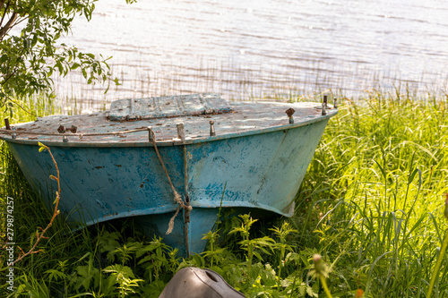 Blue boat on the lake in the green grass