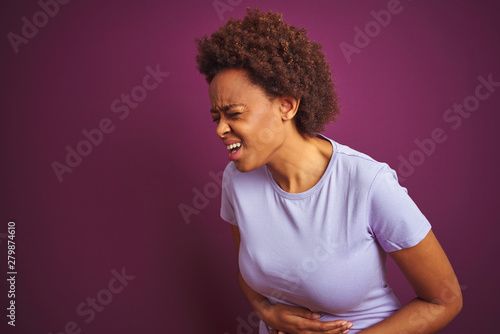 Young beautiful african american woman with afro hair over isolated purple background with hand on stomach because nausea, painful disease feeling unwell. Ache concept.