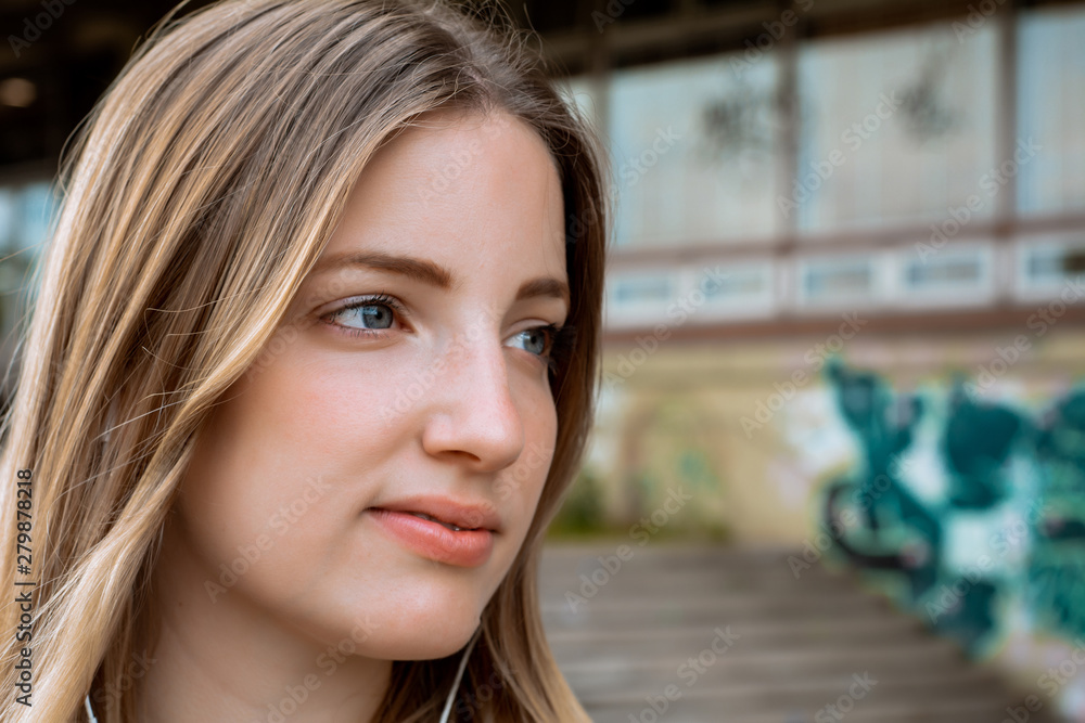 Fototapeta premium Young blond woman listening to music with earphones
