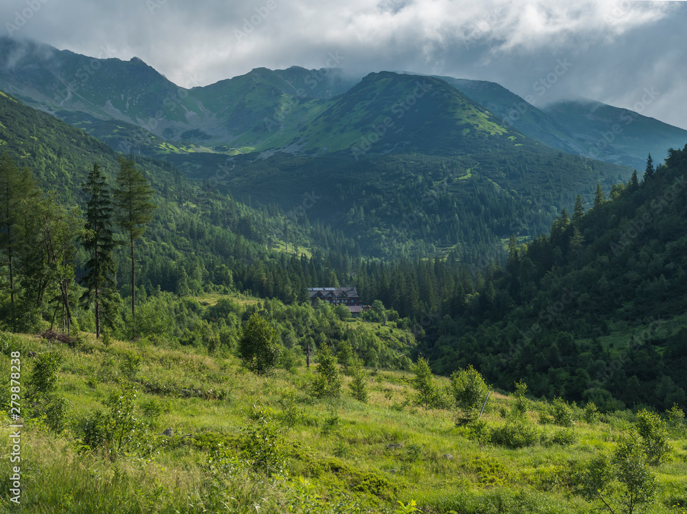 Beautiful mountain valley with mountain hut Ziarska Chata, wooden cottage, spruce trees, dwarf scrub pine and bald mountain peaks. Western Tatras mountains, Rohace Slovakia, summer, blue sky Beautiful mountain valley with mountain hut Ziarska Chata, wooden cottage, spruce trees, dwarf scrub pine and bald mountain peaks. Western Tatras mountains, Rohace Slovakia, summer, blue sky