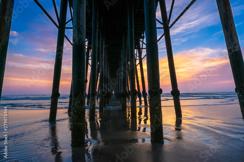 Beautiful sunset sky through second longest wooden pier over the beach and ocean at Oceanside pier - California, USA.