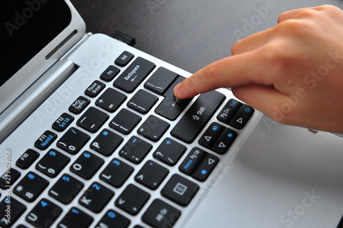 Woman hand touching laptop computer keyboard - Focus on the keyboard