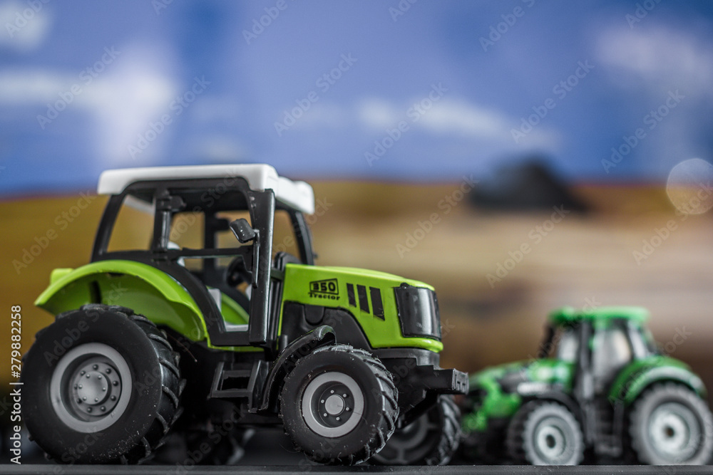 Two children's tractors on a blurred background of the field Two children's tractors on a blurred background of the field