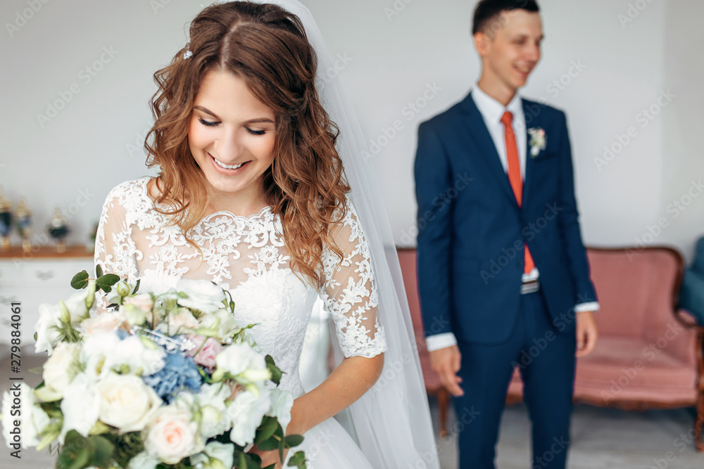 Beautiful bride in white dress and groom in suit, posing in white Studio interior, wedding