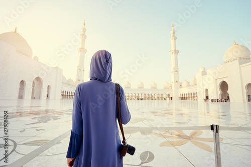 Traveling by Unated Arabic Emirates. Woman in traditional abaya standing in the Sheikh Zayed Grand Mosque, famous Abu Dhabi sightseeing. photo