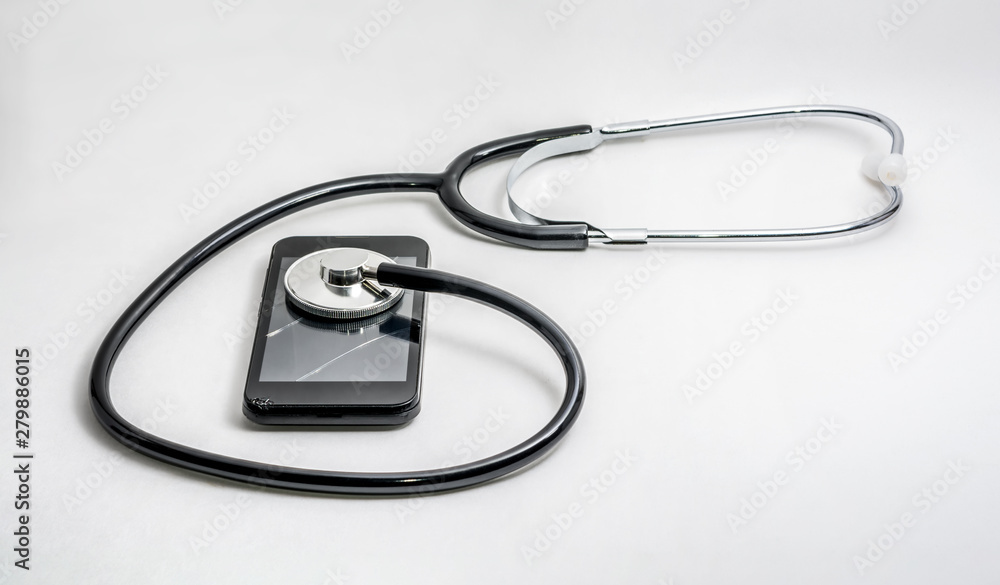 Old crushed mobile phone with a broken screen and a stethoscope on a white background. Concept of mobile service. Recovery and repair.
