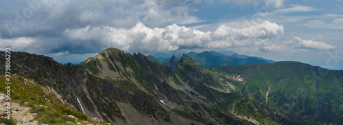 Panoramic view from Banikov peak on Western Tatra mountains or Rohace panorama. Sharp green mountains - ostry rohac  placlive and volovec with hiking trail on ridge. Summer blue sky white clouds.