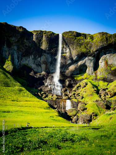 Waterfall in green mountain landscape in Iceland