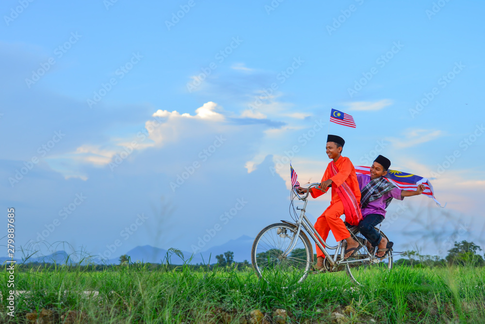 independence Day concept - Two happy young local boy riding old bicycle at paddy field holding a Malaysian flag independence Day concept - Two happy young local boy riding old bicycle at paddy field holding a Malaysian flag