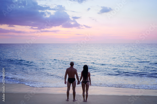 Romance on the sea shore. Silhouette of a couple in love holding hands on a sunset tropical background.