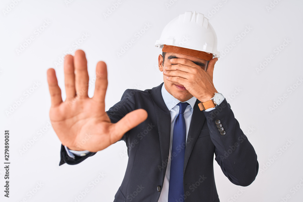 Young handsome architect man wearing suit and helmet over isolated white background covering eyes with hands and doing stop gesture with sad and fear expression. Embarrassed and negative concept. Young handsome architect man wearing suit and helmet over isolated white background covering eyes with hands and doing stop gesture with sad and fear expression. Embarrassed and negative concept.