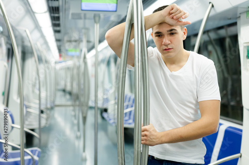 Tired man standing in underground carriage