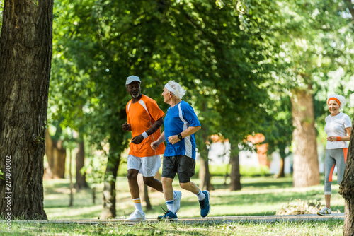 selective focus of happy multicultural men running with retired woman