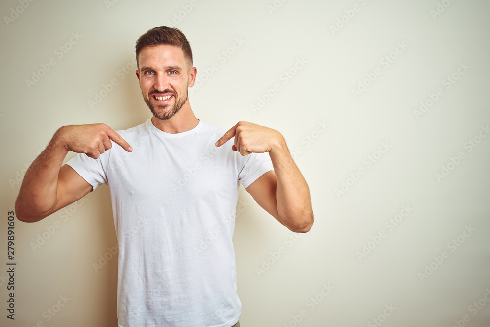Young handsome man wearing casual white t-shirt over isolated background looking confident with smile on face, pointing oneself with fingers proud and happy. Young handsome man wearing casual white t-shirt over isolated background looking confident with smile on face, pointing oneself with fingers proud and happy.